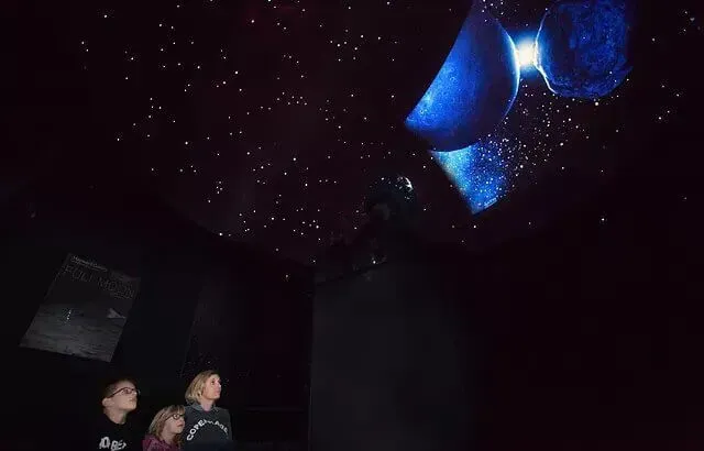 A family inside the dark room at Southend Planetarium, looking at the stars.