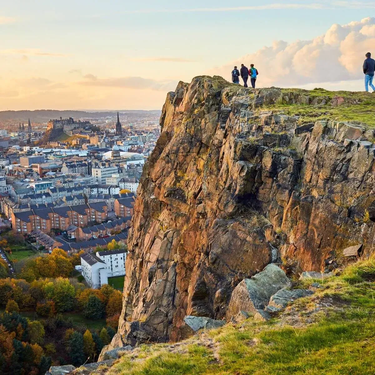 People standing on the summit of Arthur's Seat, with Leith in the distance.