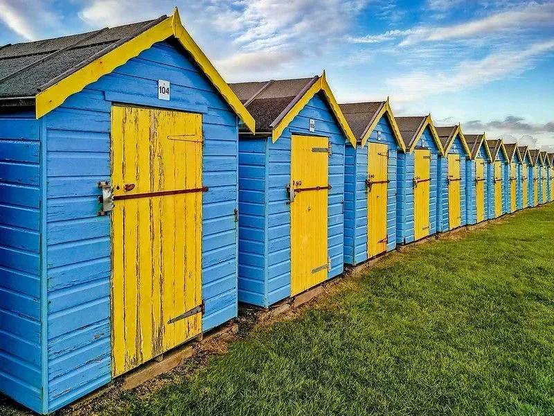Colourful blue and yellow beach huts lined up on the grass at Bognor Regis Beach.
