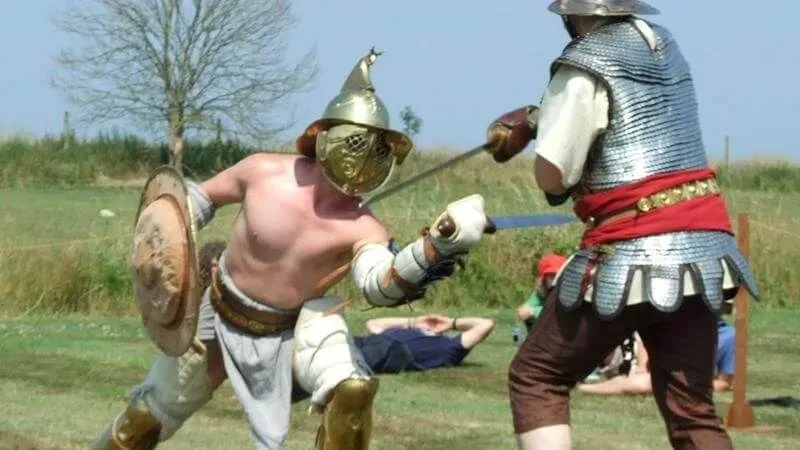 Two actors in Roman gladiator gear having a re-enactment fight at Bignor Roman Villa & Museum.