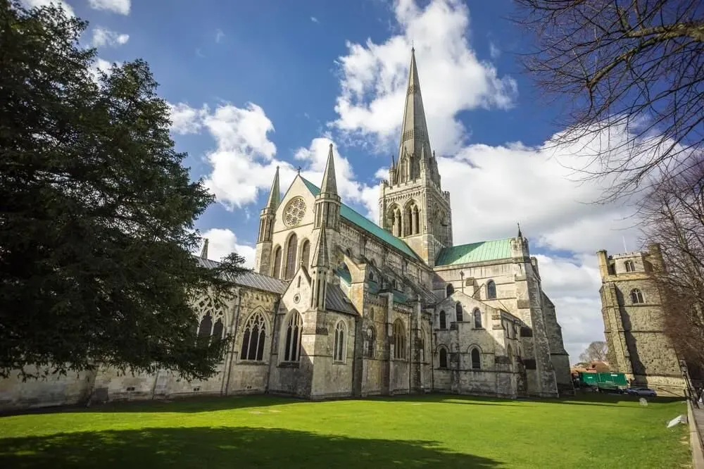 The exterior of Chichester Cathedral against a blue sky with clouds.