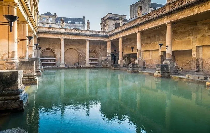 A view of the blue-green water and the surrounding columns of the Great Bath at the Roman Baths.