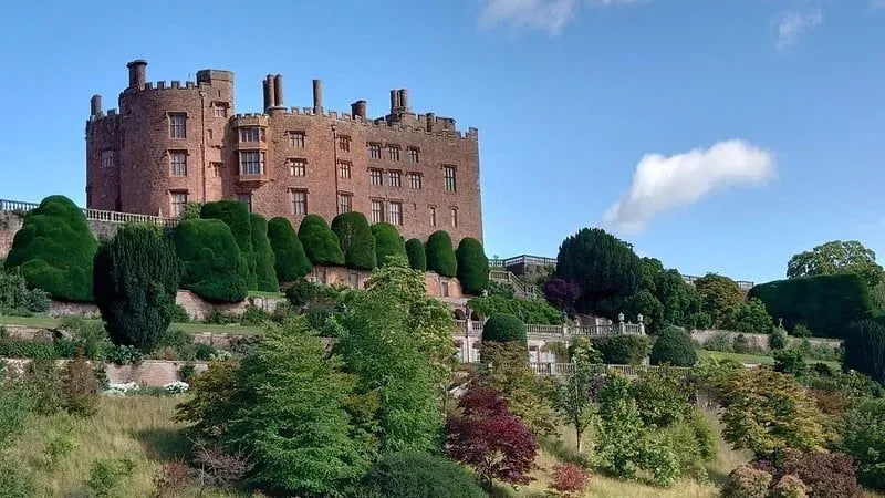 The exterior of Powis Castle sitting high on a rock with the formal gardens underneath.
