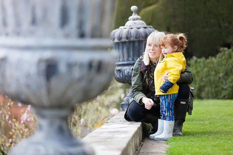 A mother and daughter standing next to a lead statue in the Powis Castle garden.   