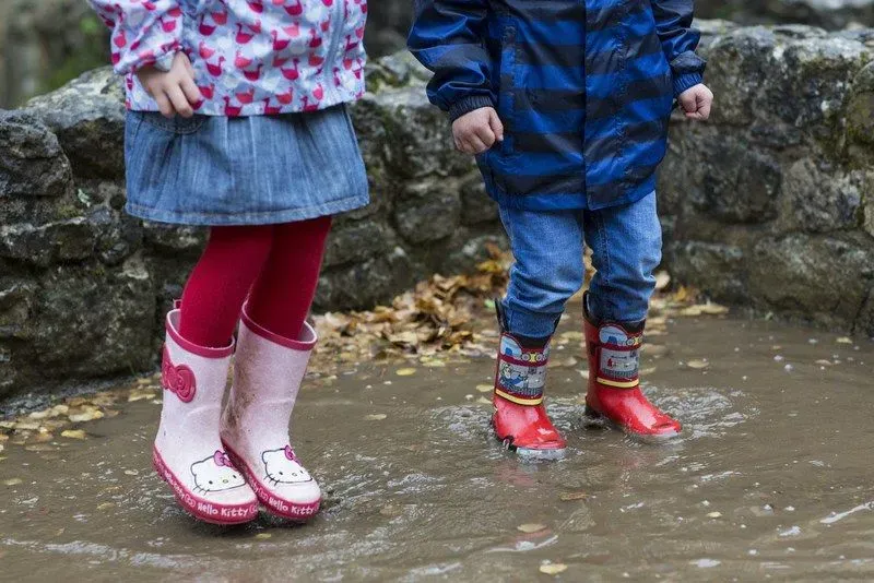 Kids in wellies jumping in water at Croft Castle and Parkland.