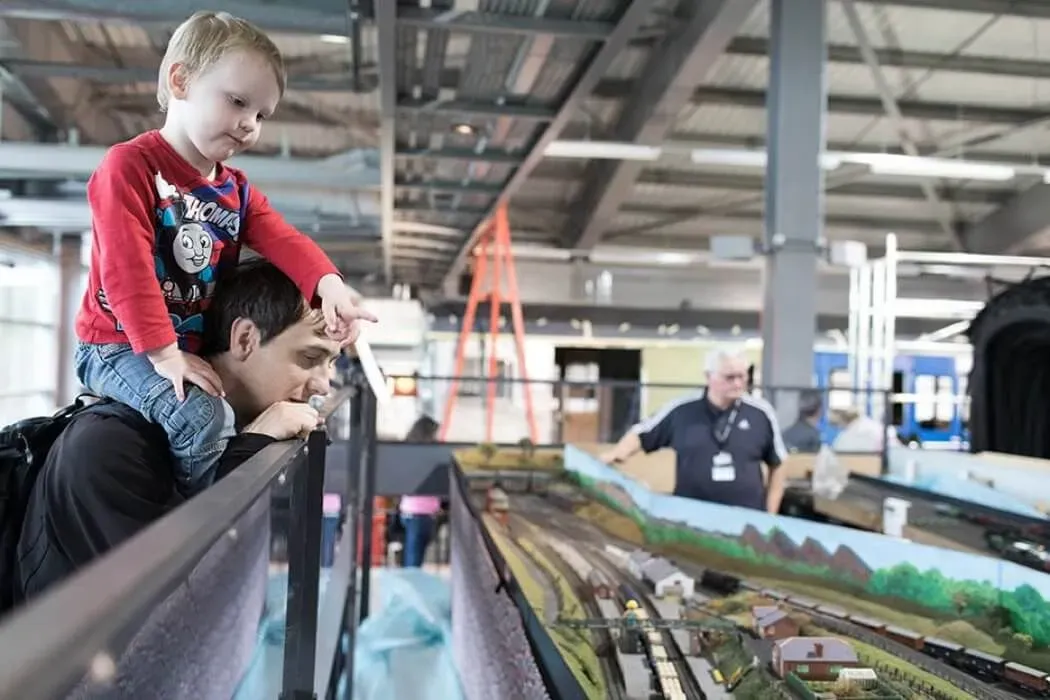 A child sitting on the shoulders of his dad looking at the display at Locomotion.