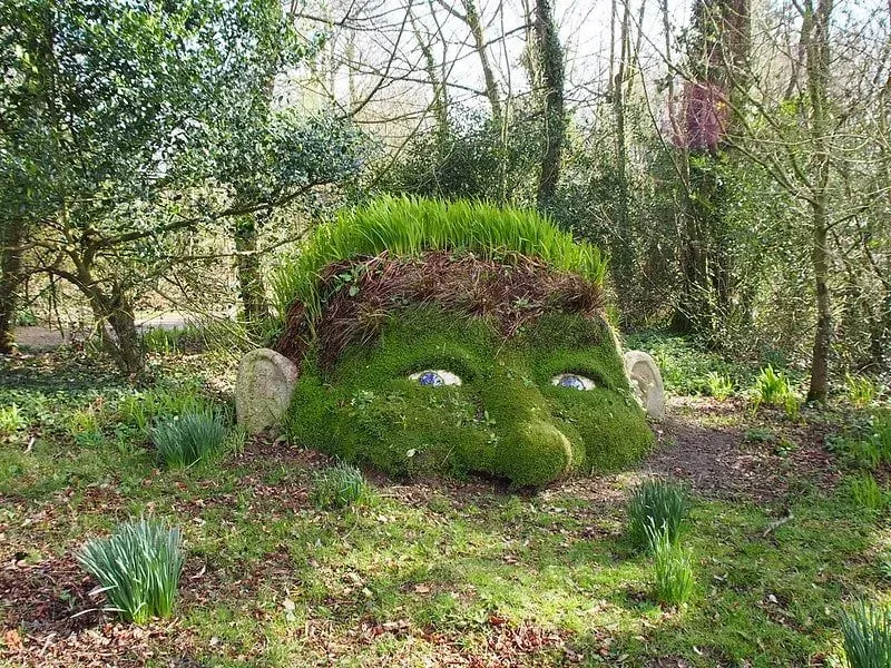 Lost Gardens of Heligan statue, head half out of the ground with open eyes.