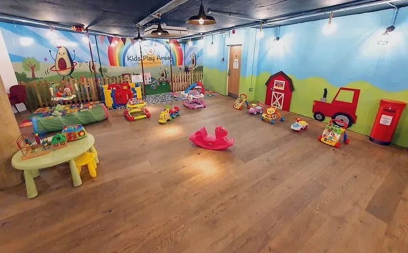The large AvoCuddle Playroom with wooden floors, colourful walls and toys dotted around.