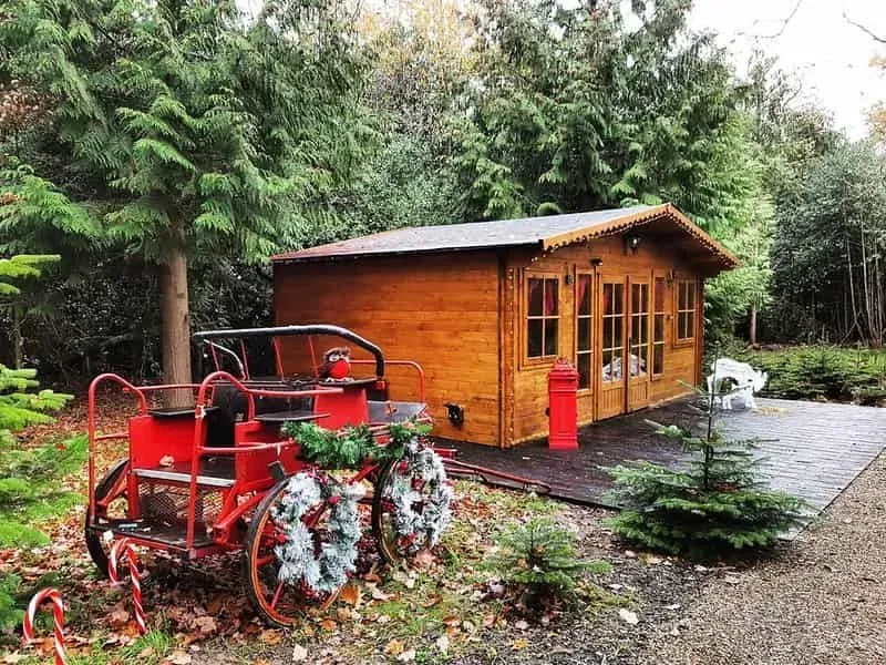 A wooden cabin at Magic of Foresters with a festive truck in front of it.