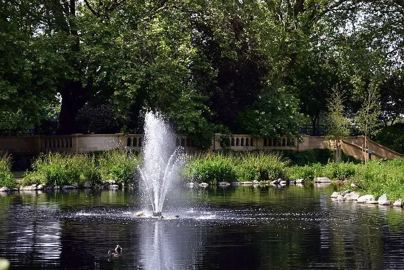 Bishops Park fountain in the lake with a bridge in the background.