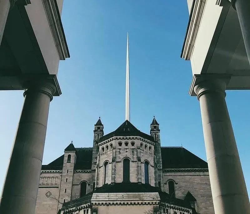 Exterior shot of Belfast Cathedral looking up at its tall spire on a sunny day.