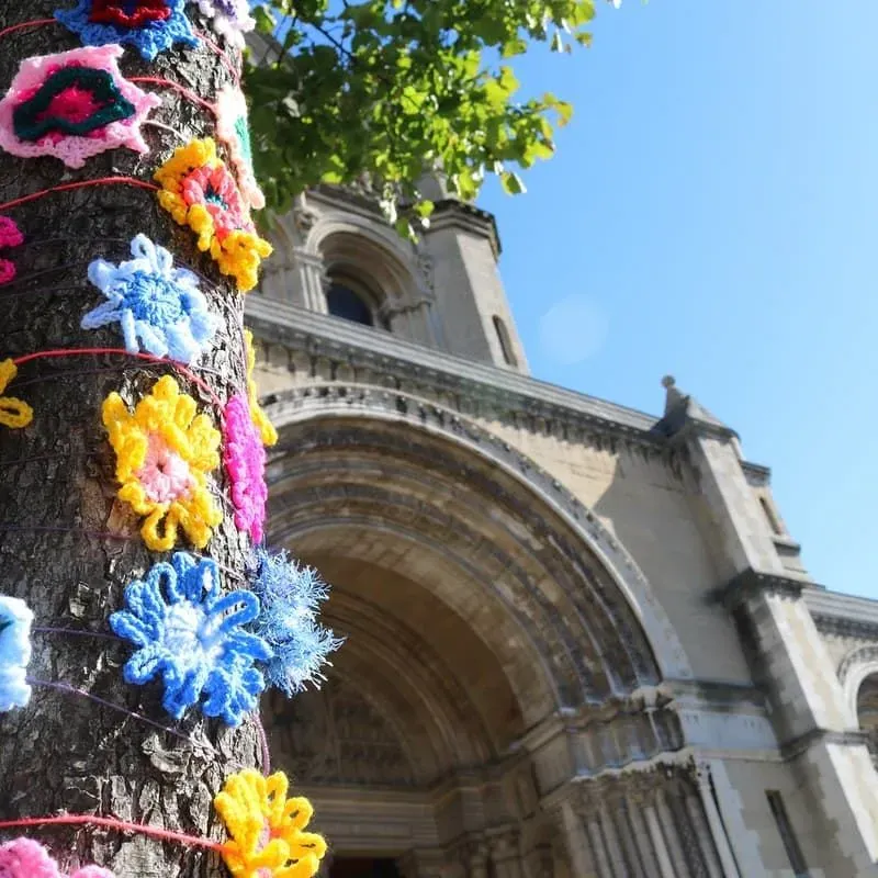 The entrance to Belfast Cathedral where a tree is lined with flowers.