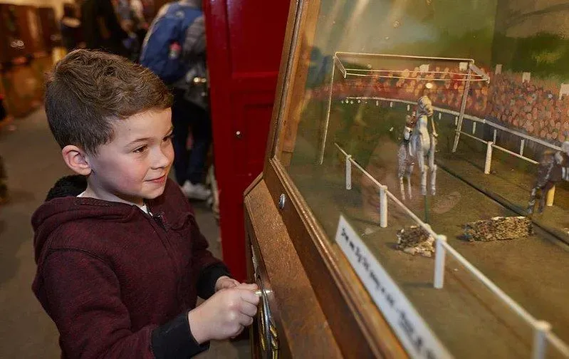 Young boy looking at a Victorian figurine set.