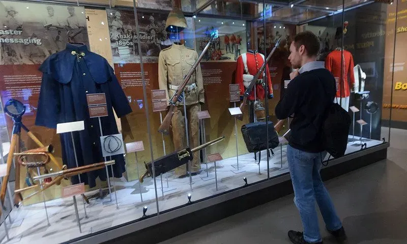 Man looking at exhibition of old war clothes.
