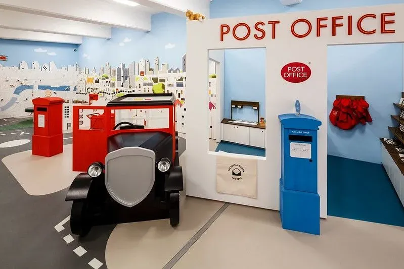 Life size model of postal office with post box and car.