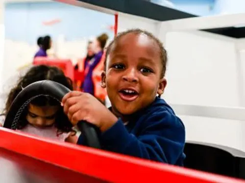 Child driving red car at The Postal Museum.