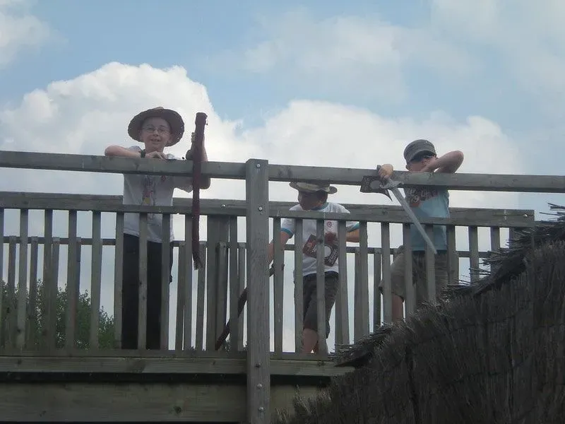 Three boys dressed up standing on a bridge smiling.