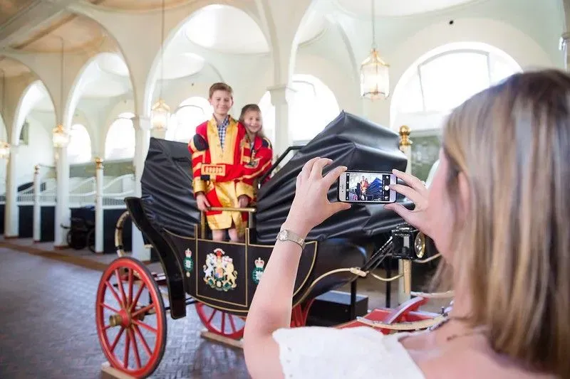 A family taking in a photo in one of the carriages at the Royal Mews.
