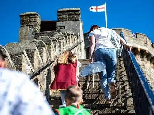 Family climb the ramparts of Warwick Castle.