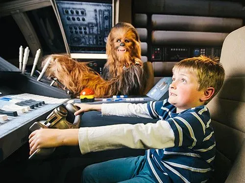 Child pretending to fly the Millennium Falcon with Chewbacca figure at Madame Tussauds.