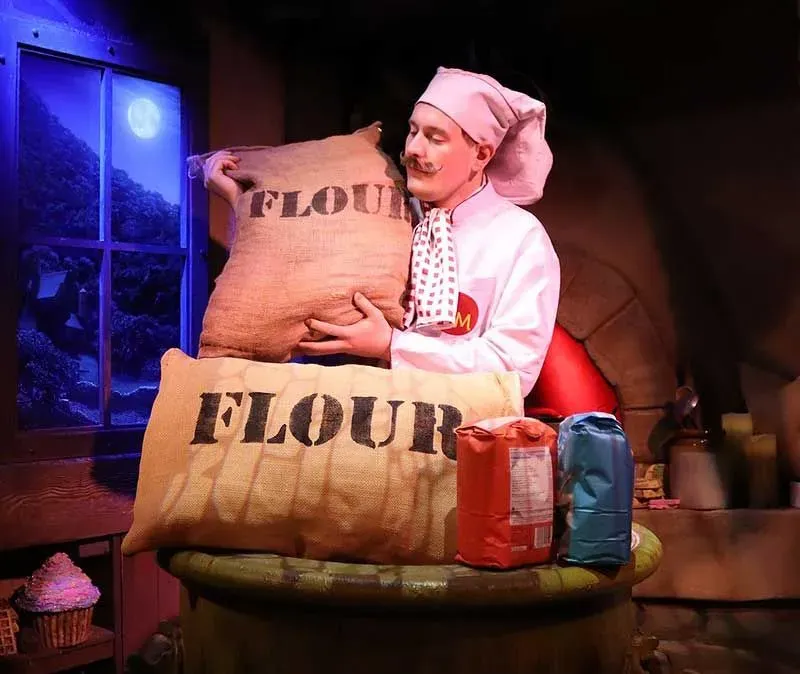 Baker holding bags of flour at Shrek's Adventure.