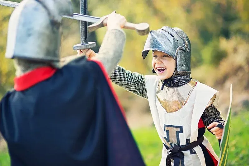 Two children dressed as knights in battle.