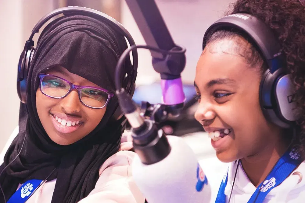 Two young girls practising being radio DJs.