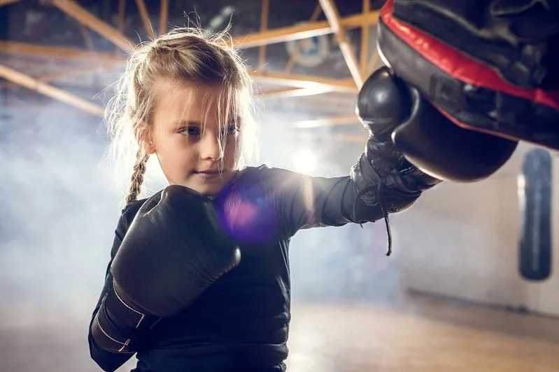 Young girl undergoing boxing training in black gloves