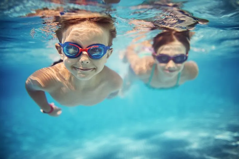 Two children swimming underwater with goggles