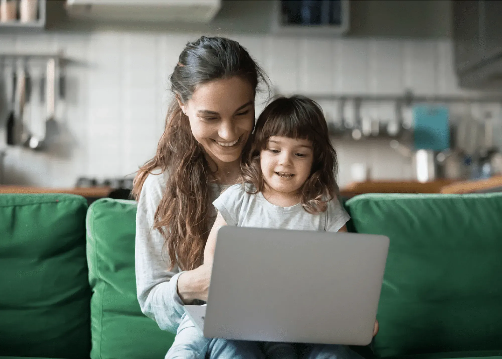 A woman and her child sat at a laptop together, smiling