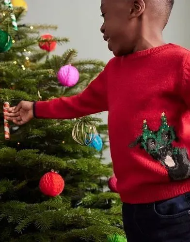 Little boy decorating tree in Joules Christmas jumper