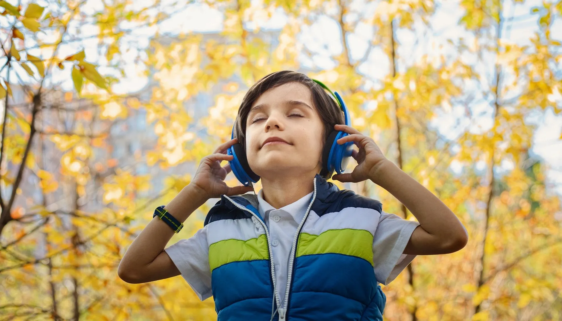 A young boy listens to music in the park.
