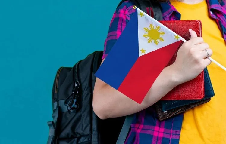 Young girl with school stuff holding Philippines flag