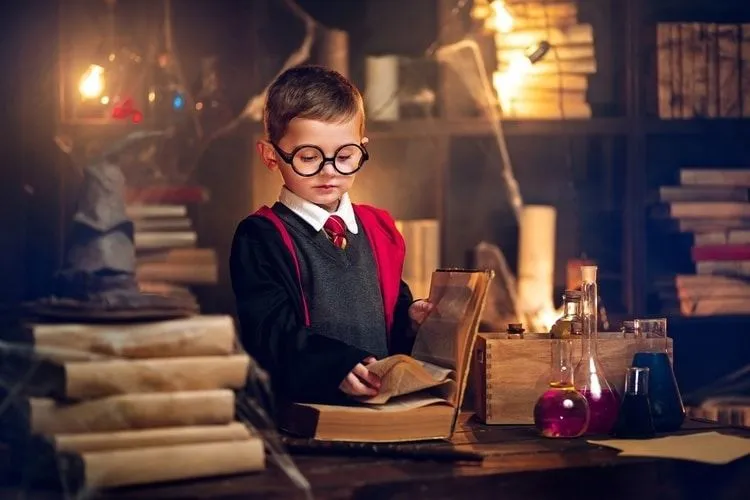 A boy dressed as a wizard learning from magic book