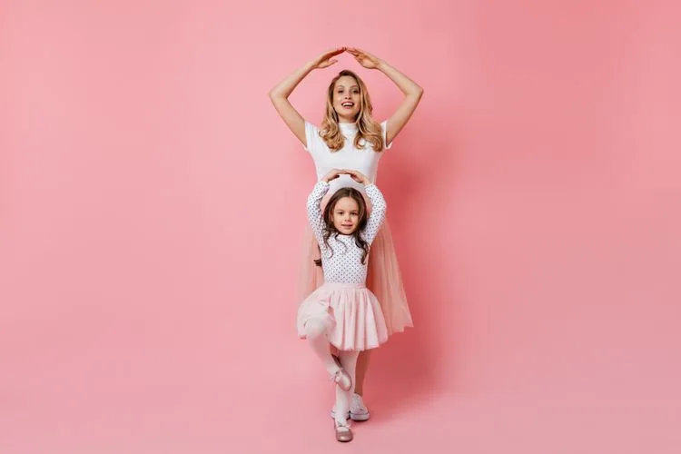 Mother and daughter posing as ballerinas in front of pink background