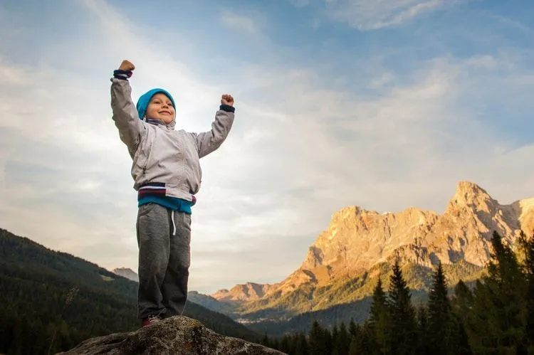 A boy feeling victorious after climbing a mountain