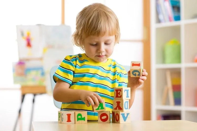 A little boy playing with alphabet wooden cubes
