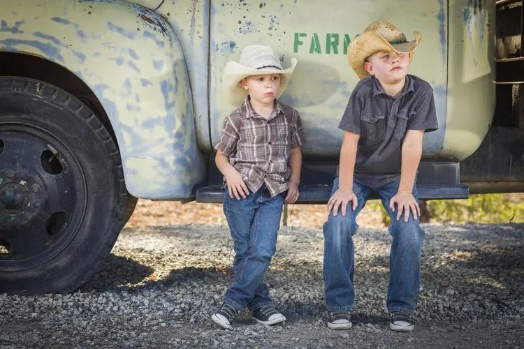 Two Young Boys Wearing Cowboy Hats Leaning Against an Antique Truck