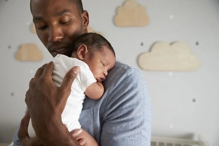 A father holding a sleeping newborn baby in his arms