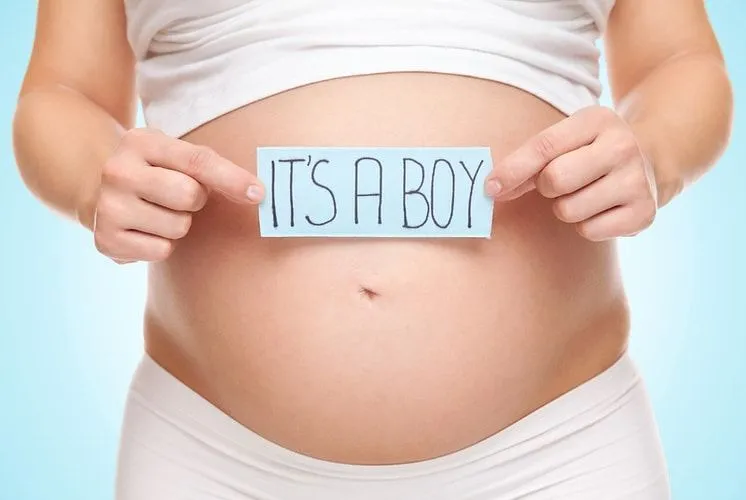 A woman holding a card against her pregnant belly