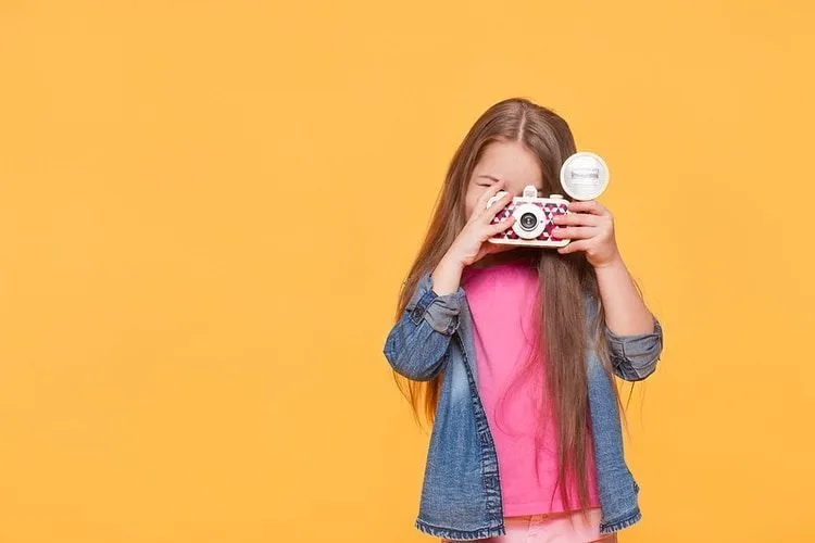 Girl posing with camera toy