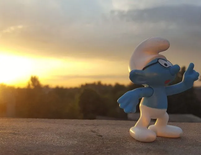Blue Smurf figurine against sunset in background