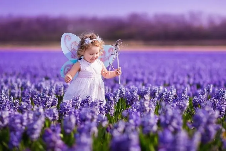 Mystical young girl with wings and wand running in lavender field - Baby names