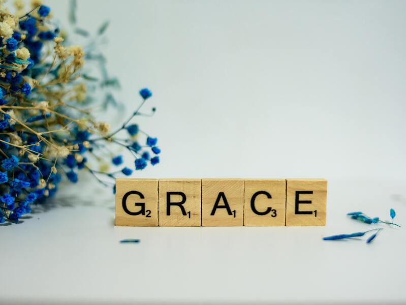 Grace words written on wooden blocks placed next to blue flowers