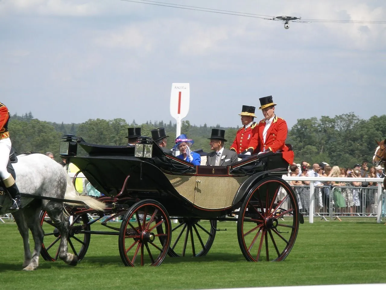 Queen Elizabeth and her royal family is parading in a horse chariot