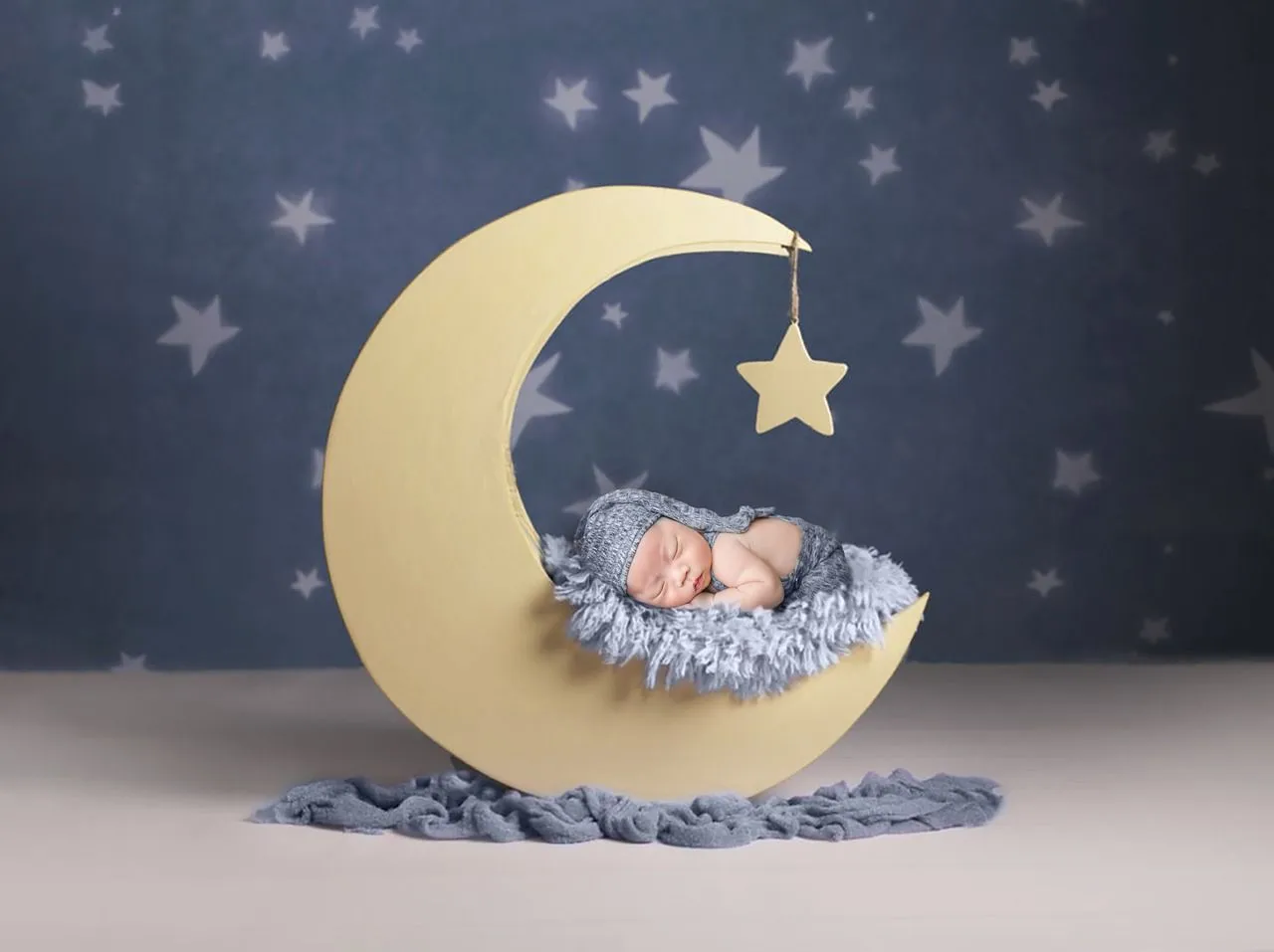A newborn baby sleeping under the star in a moon shaped cradle