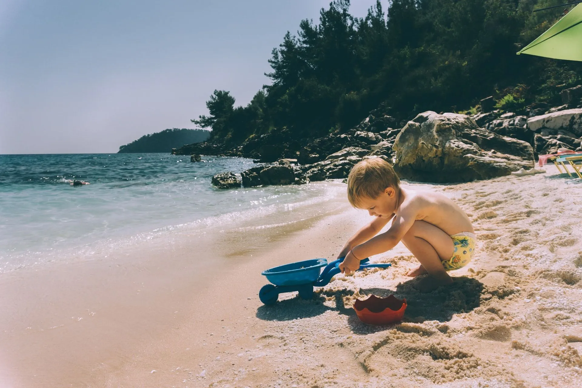 A toddler playing in sand on beach