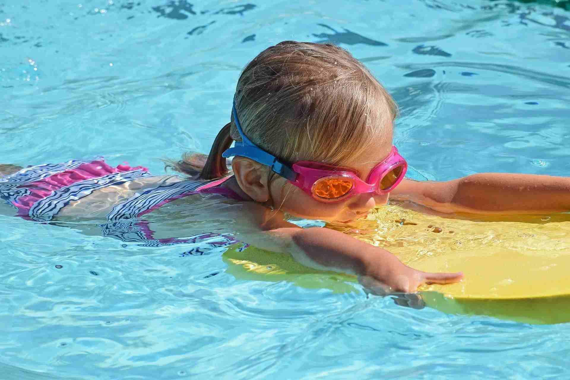 Girl wearing goggles swimming in pool.