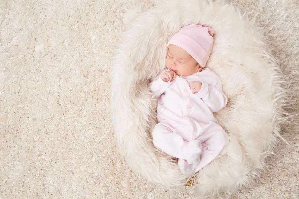 Newborn baby girl sleeping in pink fur 