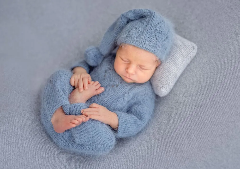 Newborn baby wearing blue knitted woolen clothes sleeping
